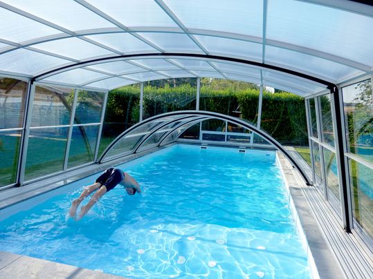 individuelle Schwimmbadüberdachungen über Pool in den ein Mann springt